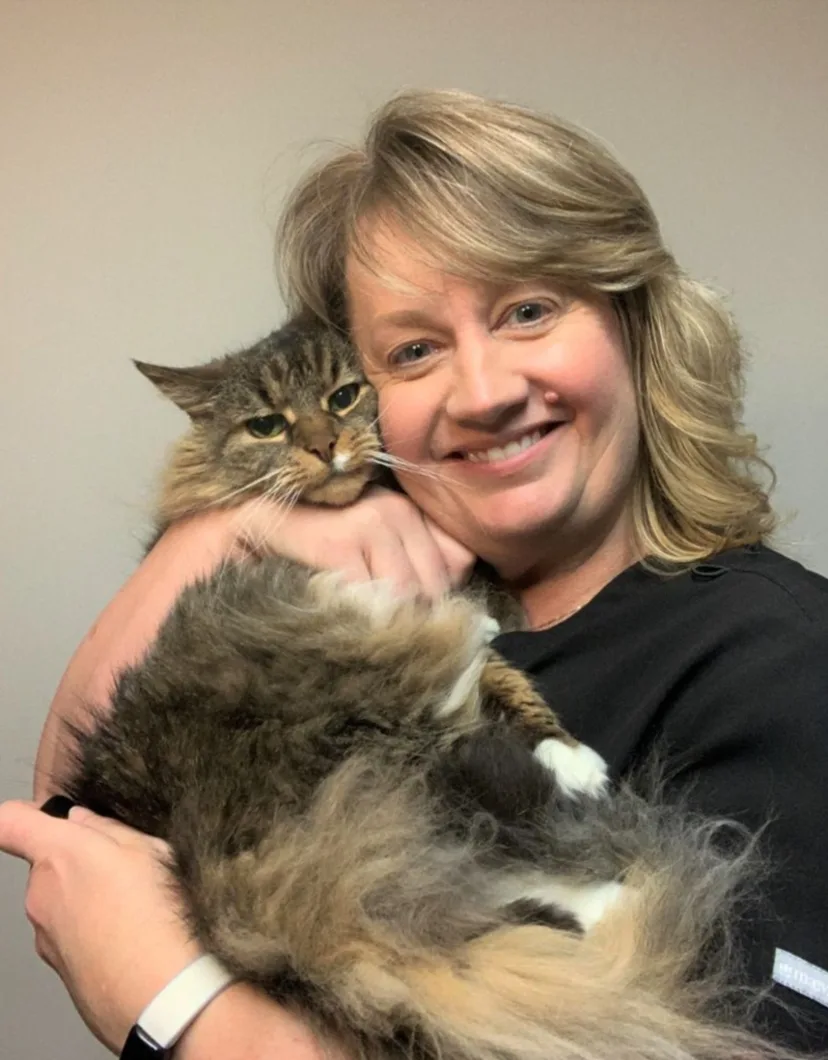 Dr. Elizabeth Patrick, DVM smiling and holding a long haired cat close to her face